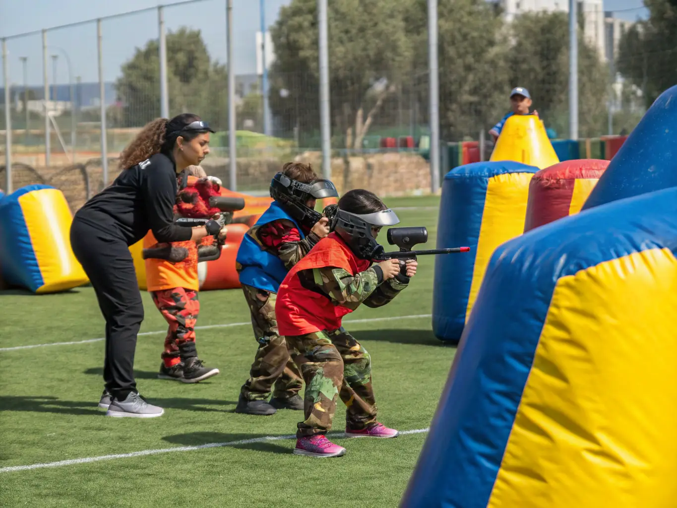 A vibrant image of children safely playing paintball in a controlled environment, emphasizing the fun and safety aspects of the youth program.